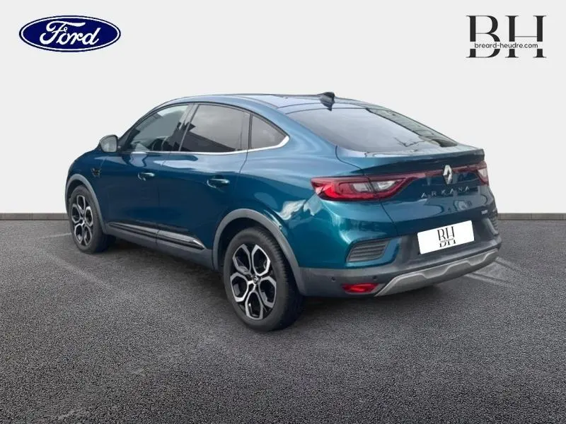 Vue 3/4 arrière droite d'un Renault Arkana bleu Zanzibar avec jantes alu et feux arrière LED distinctifs.
