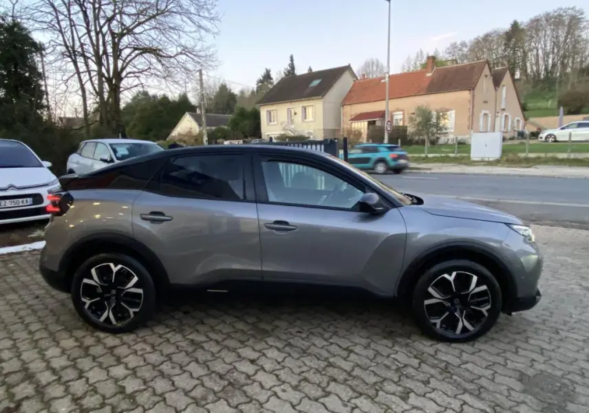 Vue latérale droite d'une Citroën C4 2025 gris foncé avec toit bi-ton noir et jantes alliage distinctives.