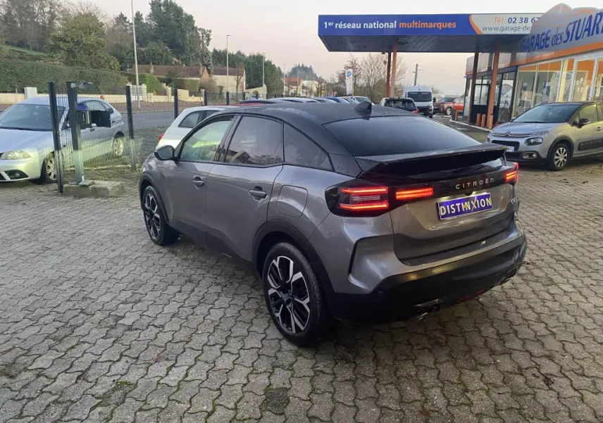 Vue 3/4 arrière droite d'une Citroën C4 gris foncé avec toit noir, feux arrière LED et jantes alliage distinctives.