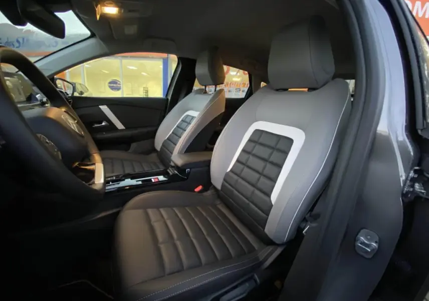 Vue intérieure côté gauche des sièges avant en cuir noir et gris clair de la Citroën C4 2025 gris foncé.