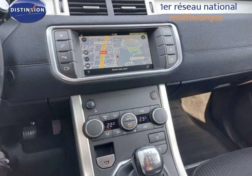 Vue rapprochée de la console centrale du Range Rover Evoque blanc 2018, avec écran tactile et levier de vitesses manuel.