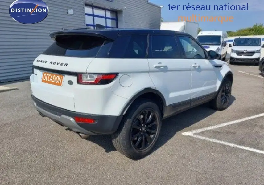Vue 3/4 arrière droite d'un Range Rover Evoque blanc de 2018 avec jantes noires et toit noir contrasté.