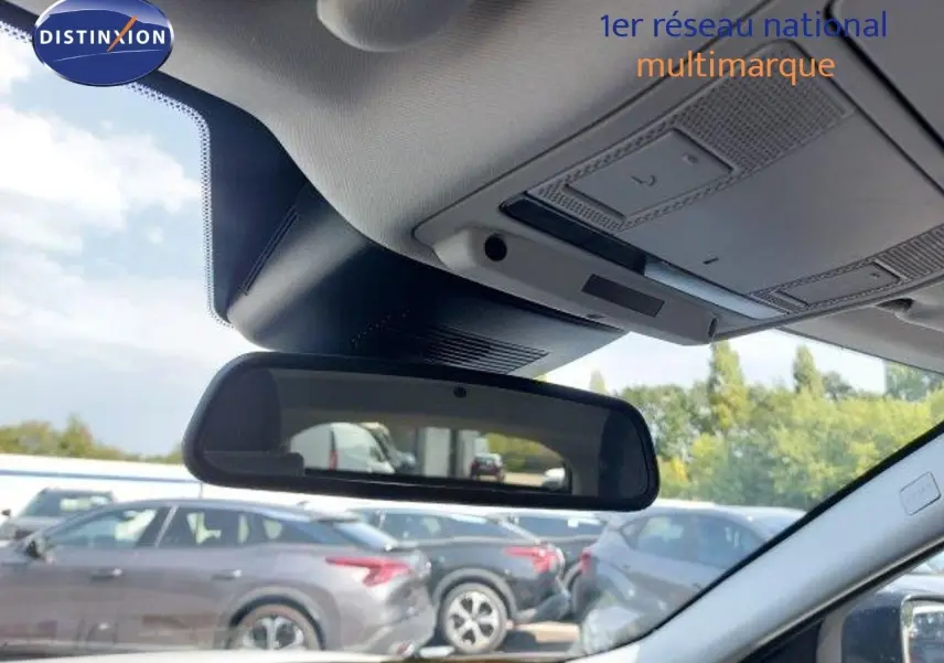 Vue intérieure du rétroviseur central du Range Rover Evoque blanc 2018, avec aperçu du ciel et véhicules en arrière-plan.