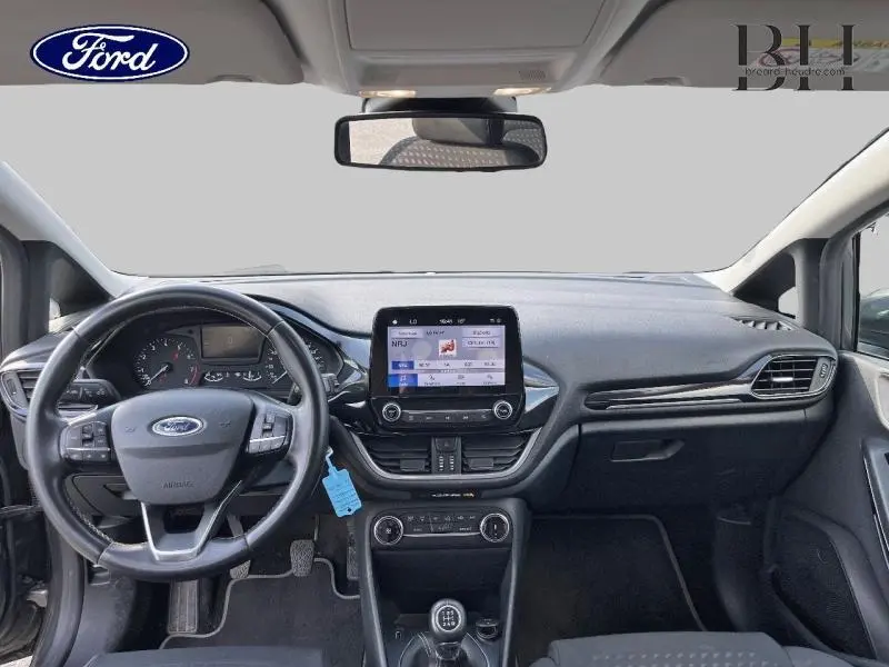Intérieur avant de la Ford Fiesta 1.1 Titanium 2021 avec tableau de bord noir, écran tactile central et volant multifonction cuir.