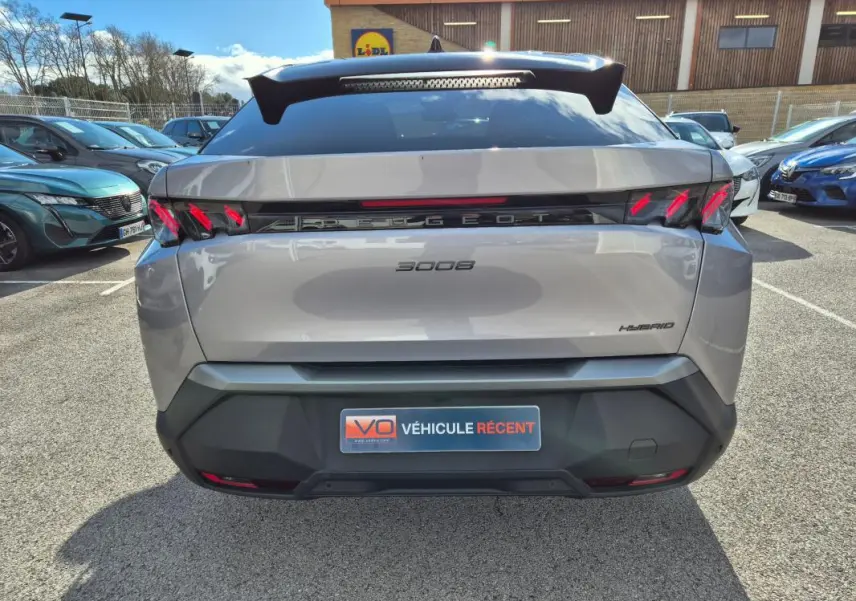 Vue arrière d’un Peugeot 3008 Hybrid gris clair 2024 avec feux arrière LED et logo Peugeot lumineux.