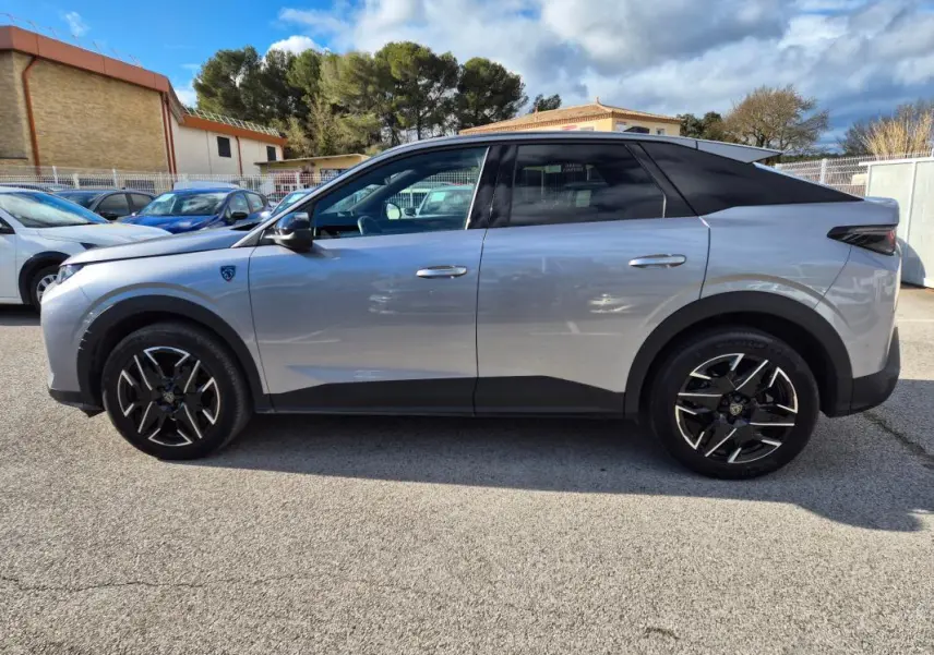 Vue de profil côté gauche d’un Peugeot 3008 Hybrid gris clair avec jantes alliage noires 19 pouces et toit noir.