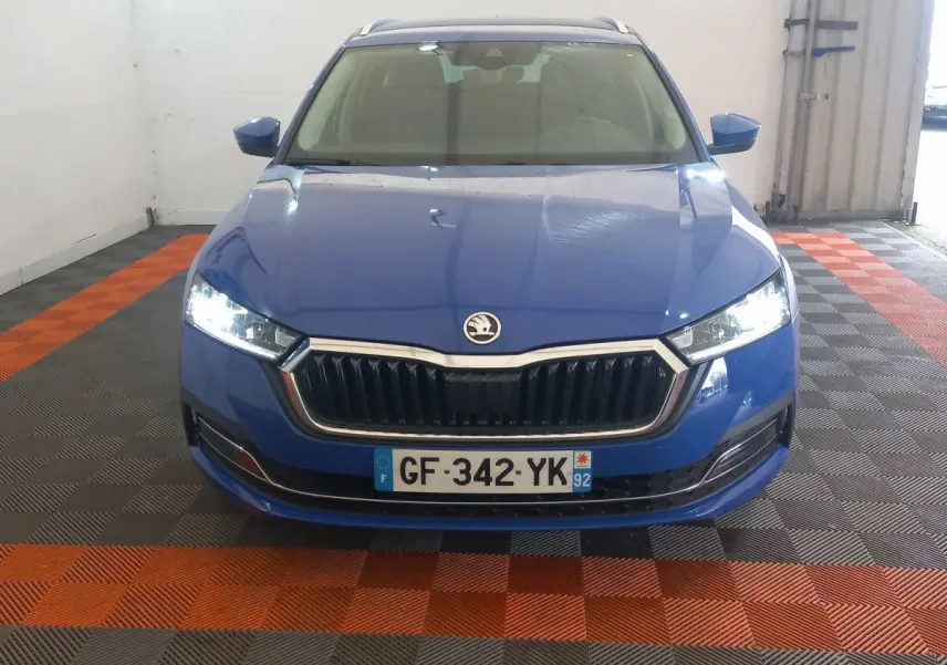 Vue frontale d'une Skoda Octavia bleu électrique avec phares LED allumés dans un garage.