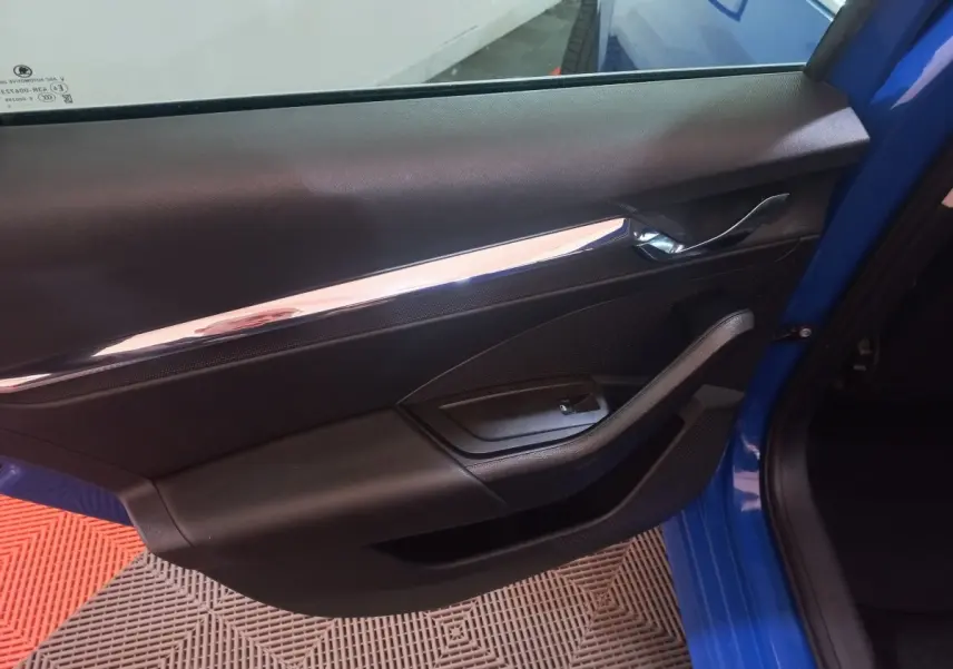 Vue rapprochée de la porte avant gauche bleue de la Skoda Octavia 2022, avec poignée chromée et commande de vitre noire.