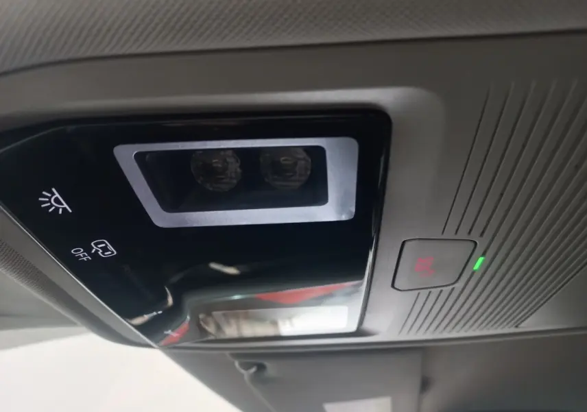 Vue intérieure du plafonnier avec bouton SOS éclairé et commandes d’éclairage dans une Skoda Octavia bleu 2022.
