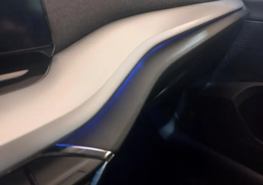 Détail intérieur du tableau de bord beige et noir de la Skoda Octavia 1.5 TSI mHEV 2022 avec éclairage d’ambiance bleu.