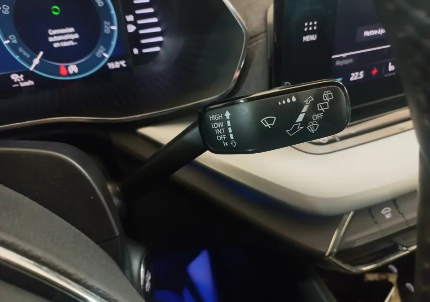 Gros plan sur la commande d’essuie-glace à gauche du volant dans l’habitacle clair de la Skoda Octavia bleue 2022.