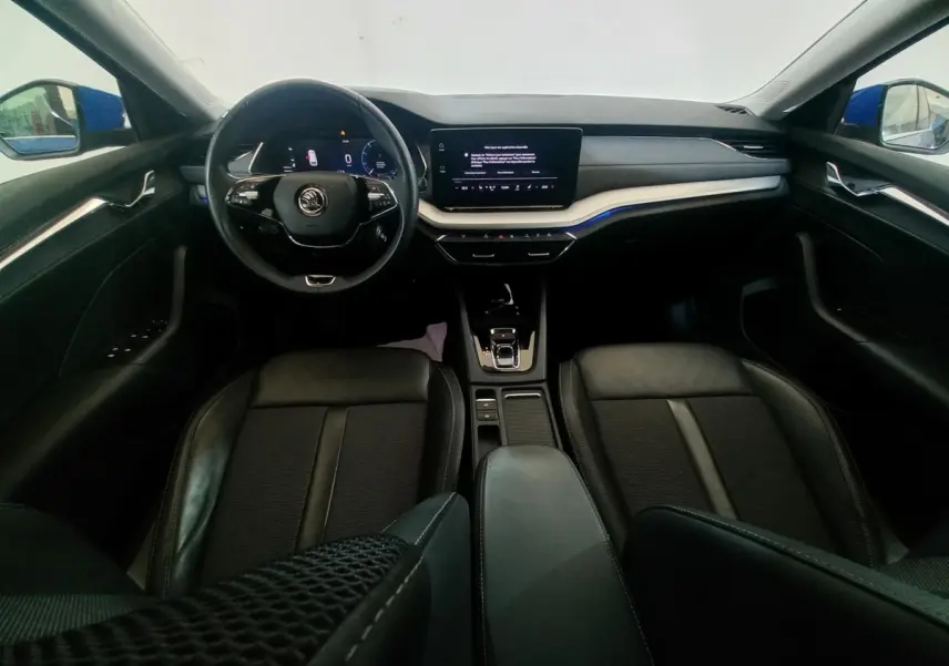 Vue intérieure avant de la Skoda Octavia 1.5 TSI mHEV 2022, tableau de bord noir avec écran tactile central et volant multifonctions.