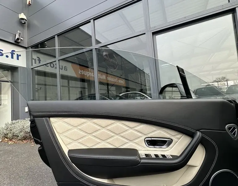 Détail de la porte côté gauche en cuir noir et beige matelassé de la Bentley Continental GT 4.0 V8 Mulliner 2013.