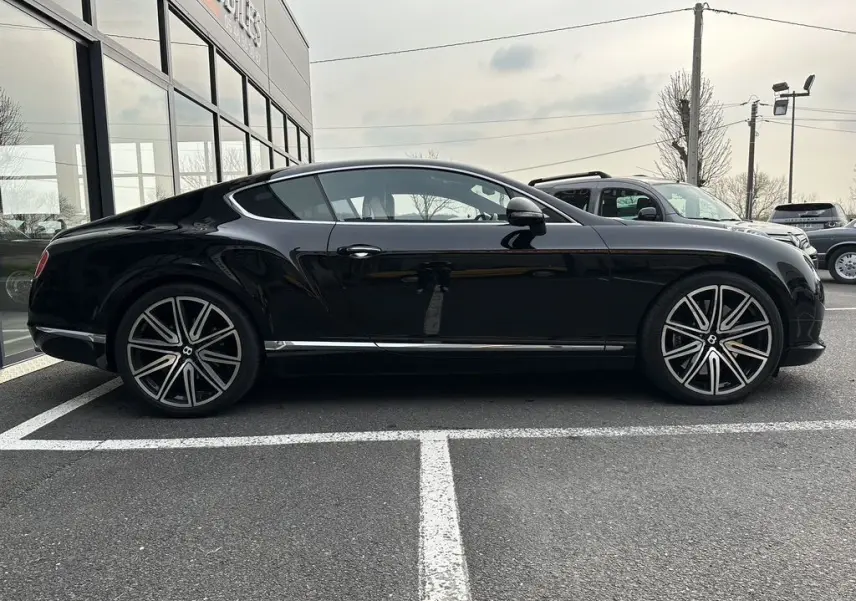 Vue de profil côté gauche d'une Bentley Continental GT noire 4.0 V8 Mulliner avec jantes alliage distinctives.