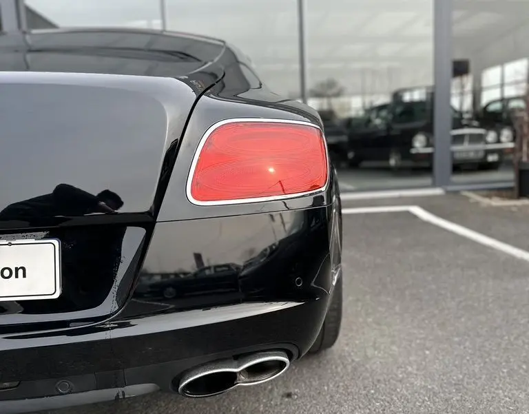 Vue arrière droite d'une Bentley Continental GT noire 4.0 V8 Mulliner de 2013, avec feu arrière et double sortie d'échappement visibles.