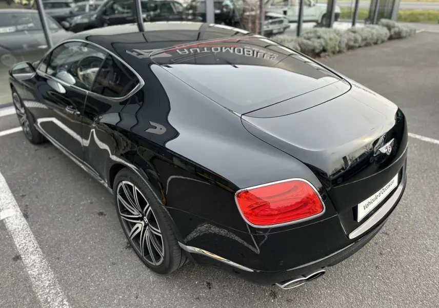 Bentley Continental GT 4.0 V8 Mulliner noire vue 3/4 arrière droit, avec feux rouges et jantes sport distinctives.