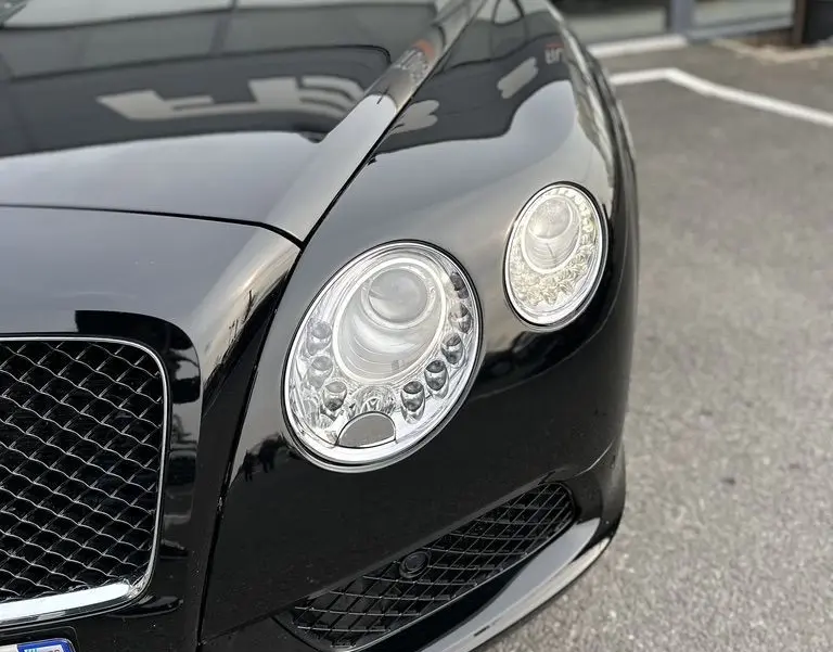 Vue rapprochée avant droite de la Bentley Continental GT Mulliner noire mettant en valeur ses phares ronds distinctifs.
