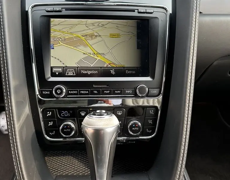 Gros plan sur la console centrale noire de la Bentley Continental GT 4.0 V8 Mulliner 2013 avec écran navigation et levier de vitesse automatique.