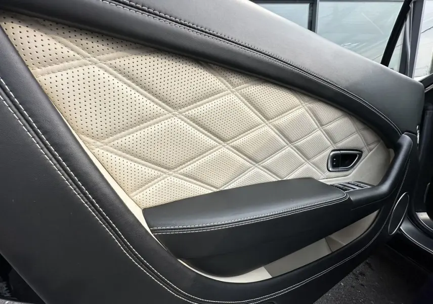 Détail de la porte côté gauche en cuir noir et beige matelassé du Bentley Continental GT 4.0 V8 Mulliner 2013.