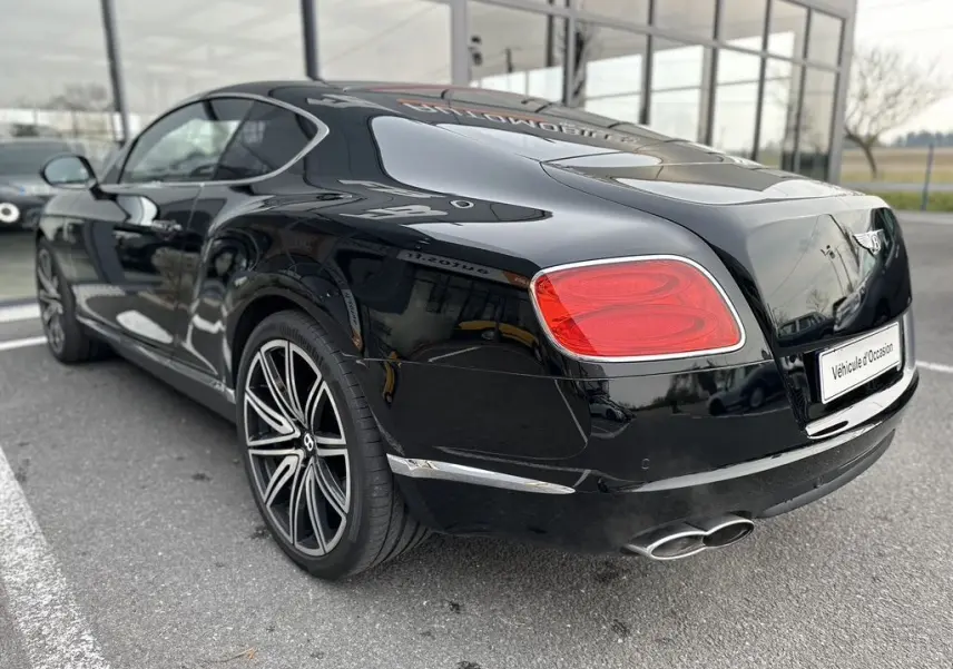 Vue 3/4 arrière droite d'une Bentley Continental GT Mulliner noire de 2013 avec jantes distinctives et double sortie d'échappement.