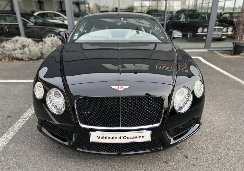 Vue frontale d'une Bentley Continental GT 4.0 V8 Mulliner noire brillante avec calandre distinctive et phares ronds.