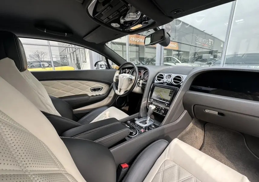 Vue intérieure côté conducteur de la Bentley Continental GT Mulliner 2013 noire avec sellerie cuir beige et noire raffinée.