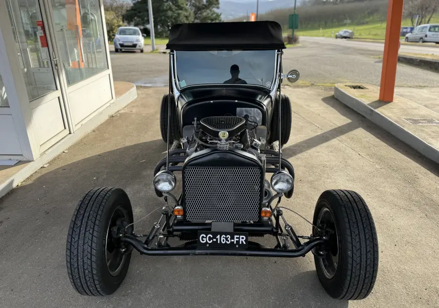 Vue frontale d'une Ford T Hot Rod V8 noire de 1923, moteur visible et capote noire relevée.