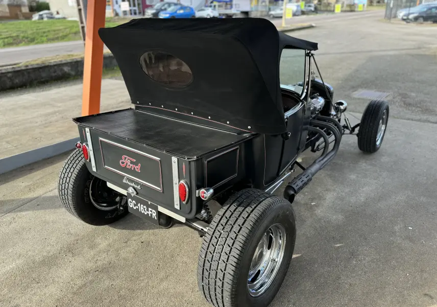 Vue 3/4 arrière droite d'une Ford T Hot Rod V8 noire décapotable avec coffre et pneus larges chromés.