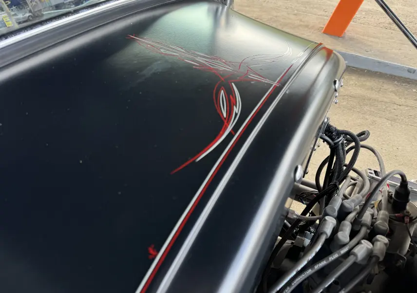 Capot noir mat avec liserés rouges et blancs fait main, vue rapprochée du moteur V8 du Ford T Hot Rod 1923.