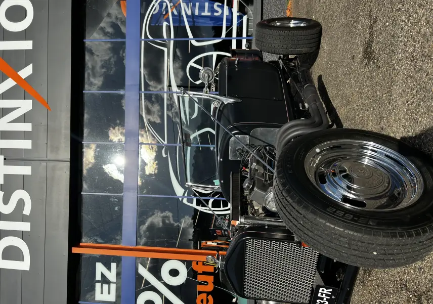 Vue de face en léger 3/4 droit d'une Ford T Hot Rod V8 noire avec moteur apparent et jantes chromées brillantes.