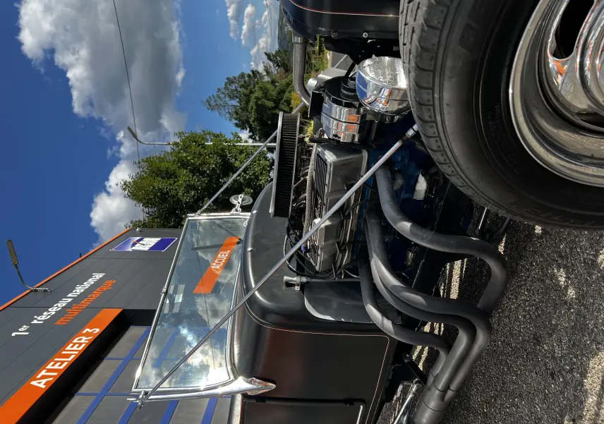 Vue 3/4 avant droit du Ford T Hot Rod V8 noir mat avec moteur V8 apparent et échappements noirs torsadés.