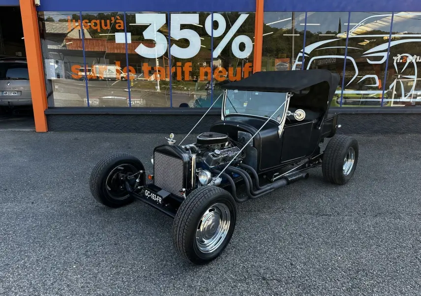 Ford T Hot Rod V8 noir vue 3/4 avant droit, capote noire et moteur V8 apparent avec échappements latéraux.
