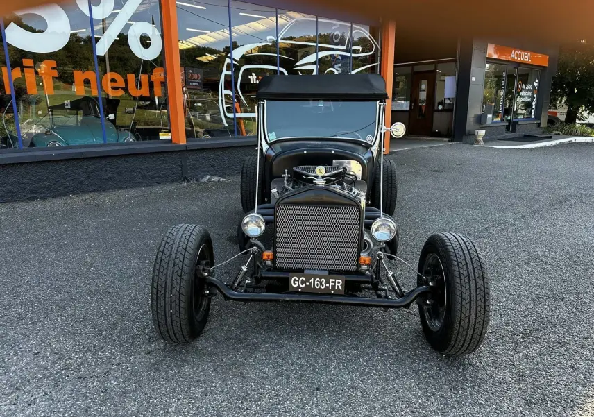 Vue frontale d'une Ford T Hot Rod V8 noire avec capote noire et calandre métallique ajourée.