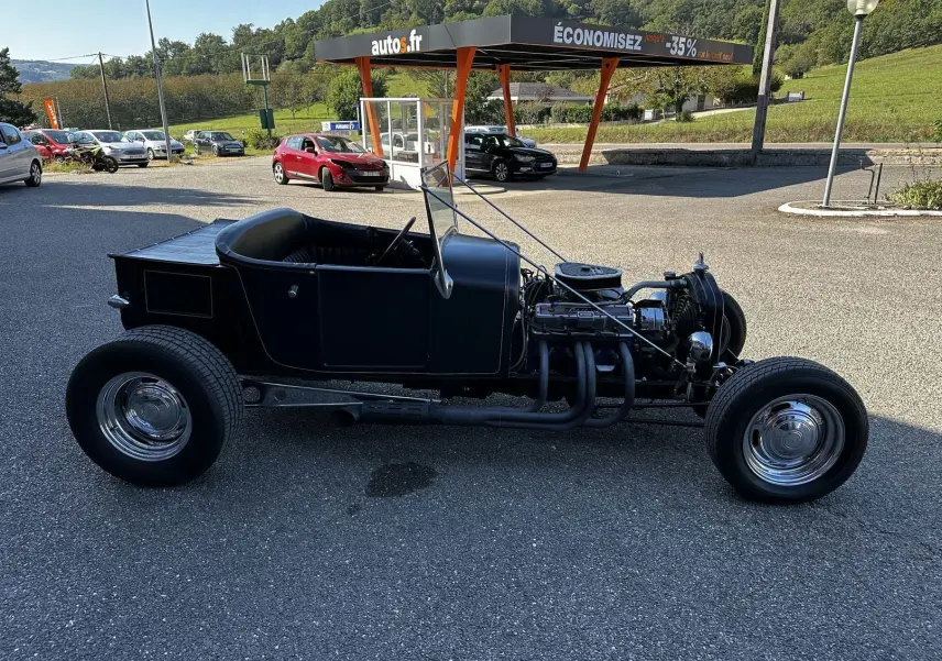Ford T Hot Rod V8 noir vue de profil côté gauche, capot moteur ouvert et intérieur décapotable visible.