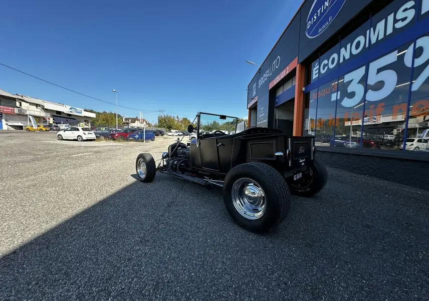 Ford T Hot Rod V8 noir vue 3/4 arrière droit, décapotable avec jantes chromées et moteur apparent.