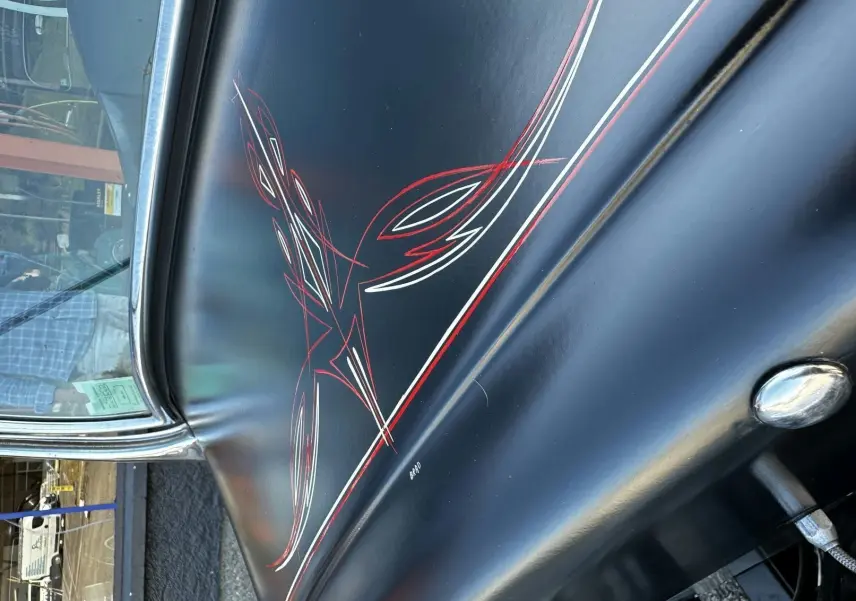 Détail de la peinture noire avec liserés rouges et blancs faits à la main sur la portière gauche d'une Ford T Hot Rod 1923.