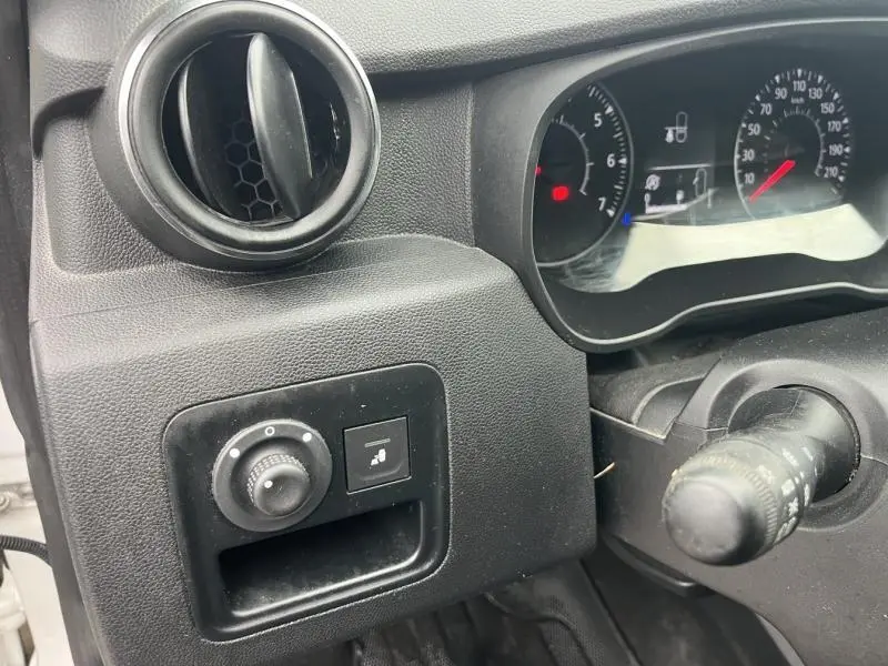 Détail du tableau de bord noir du Dacia Duster blanc Glacier 2019, avec commandes de réglage et compteurs visibles.