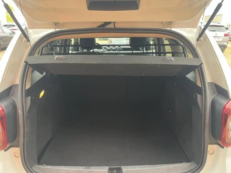 Coffre ouvert vu de l'arrière d'un Dacia Duster blanc glacier avec séparation et intérieur noir.