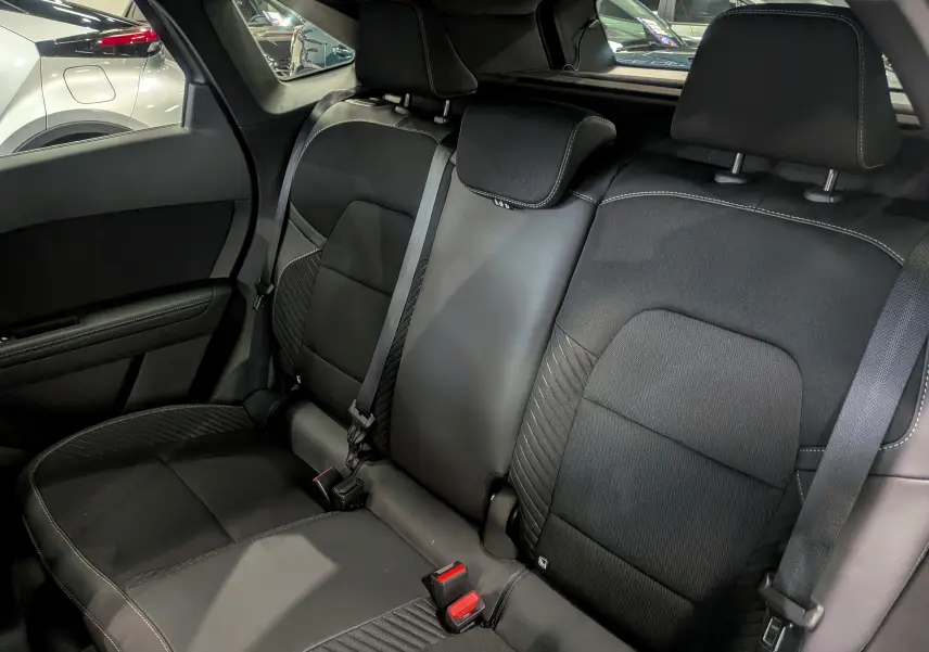 Vue intérieure arrière des sièges noirs en cuir et tissu du Renault Symbioz E-Tech 2025, avec ceinture de sécurité visible.