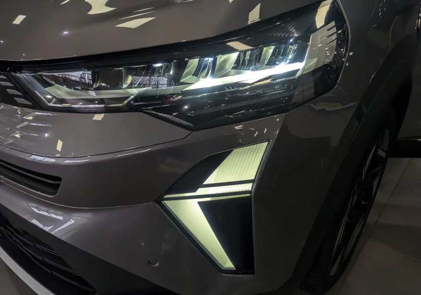 Gros plan sur le phare avant droit allumé du Renault SYMBIOZ gris Cassiopé avec éclairage LED distinctif.