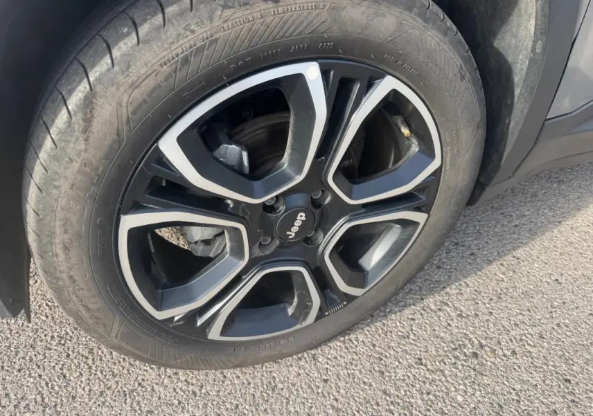 Gros plan sur la jante alliage noire et argentée de 18 pouces du Jeep Avenger gris, avec logo Jeep au centre.