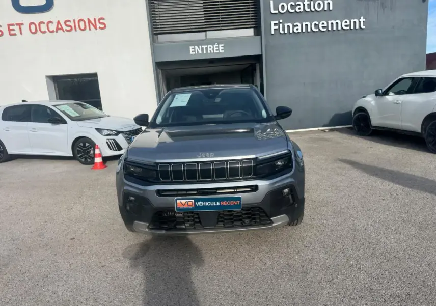 Vue de face d'un Jeep Avenger gris 2025 garé devant un bâtiment avec plaque "Véhicule récent" visible.