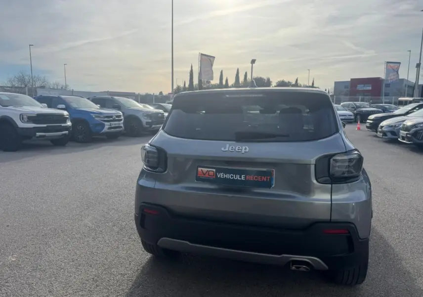 Vue arrière d'un Jeep Avenger gris 2025 garé en extérieur, avec feux arrière fumés et plaque "Véhicule récent".