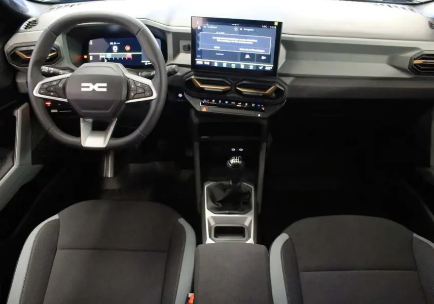 Vue intérieure avant du tableau de bord et volant cuir noir du Dacia Bigster gris schiste avec écran tactile central et boîte manuelle.
