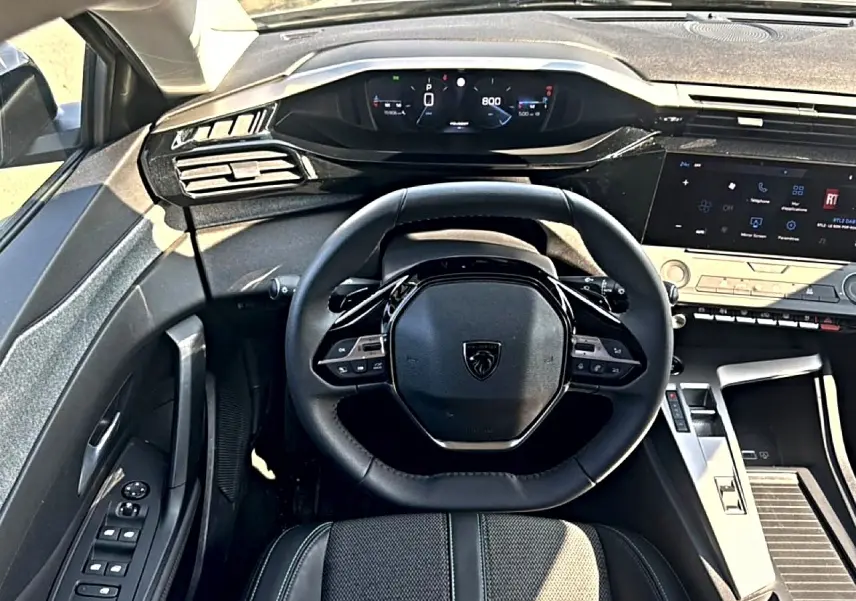 Vue intérieure centrée sur le volant multifonction et le tableau de bord numérique de la Peugeot 308 2025.