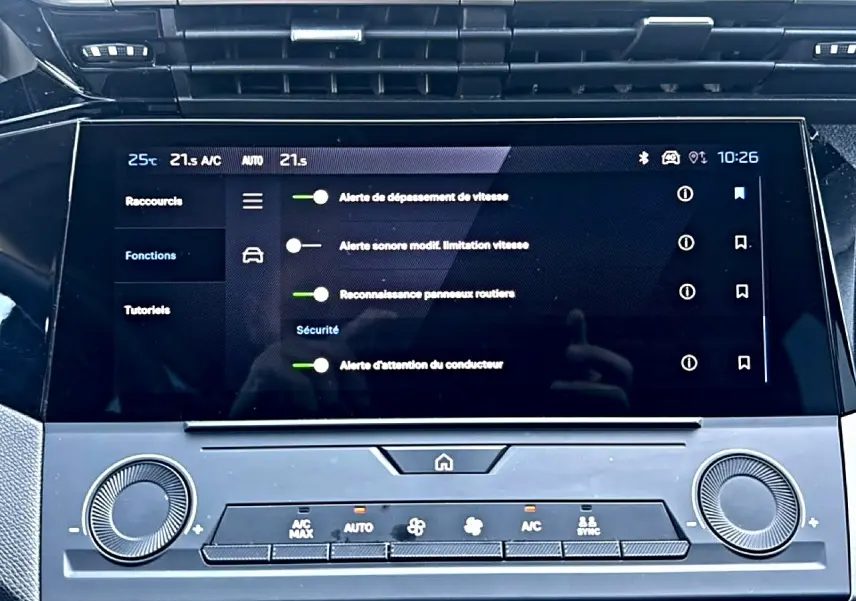 Écran tactile central de la Peugeot 308 2025 affichant les alertes de sécurité, avec commandes climatisation en dessous.