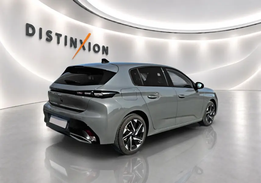 Peugeot 308 gris selenium vue 3/4 arrière droit dans un showroom lumineux avec jantes alu noires et chromées.