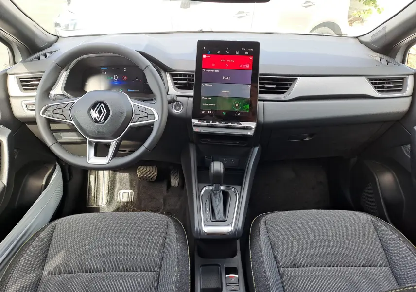 Vue intérieure avant du tableau de bord du Renault Captur gris Rafale avec écran tactile vertical et volant multifonction.