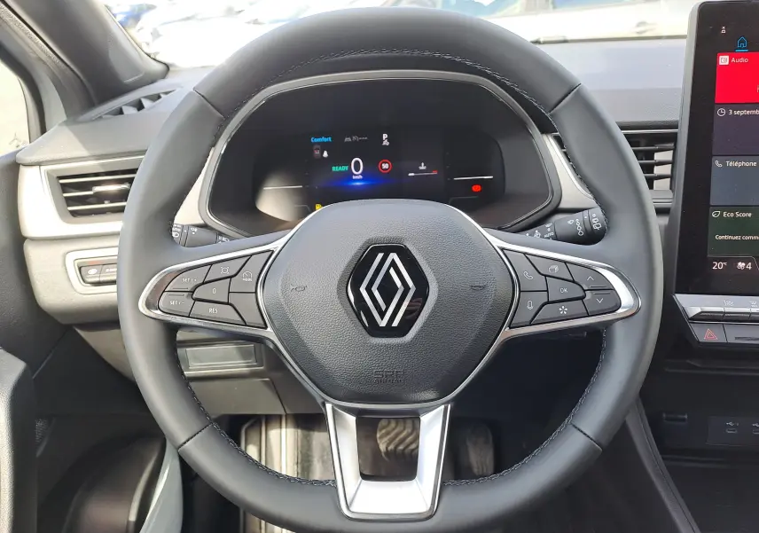 Vue rapprochée du volant noir avec logo Renault au centre du tableau de bord du Captur hybride 2025.