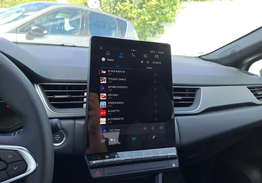 Vue intérieure du tableau de bord du Renault Captur 2025 avec écran tactile vertical et commandes climatisation visibles.